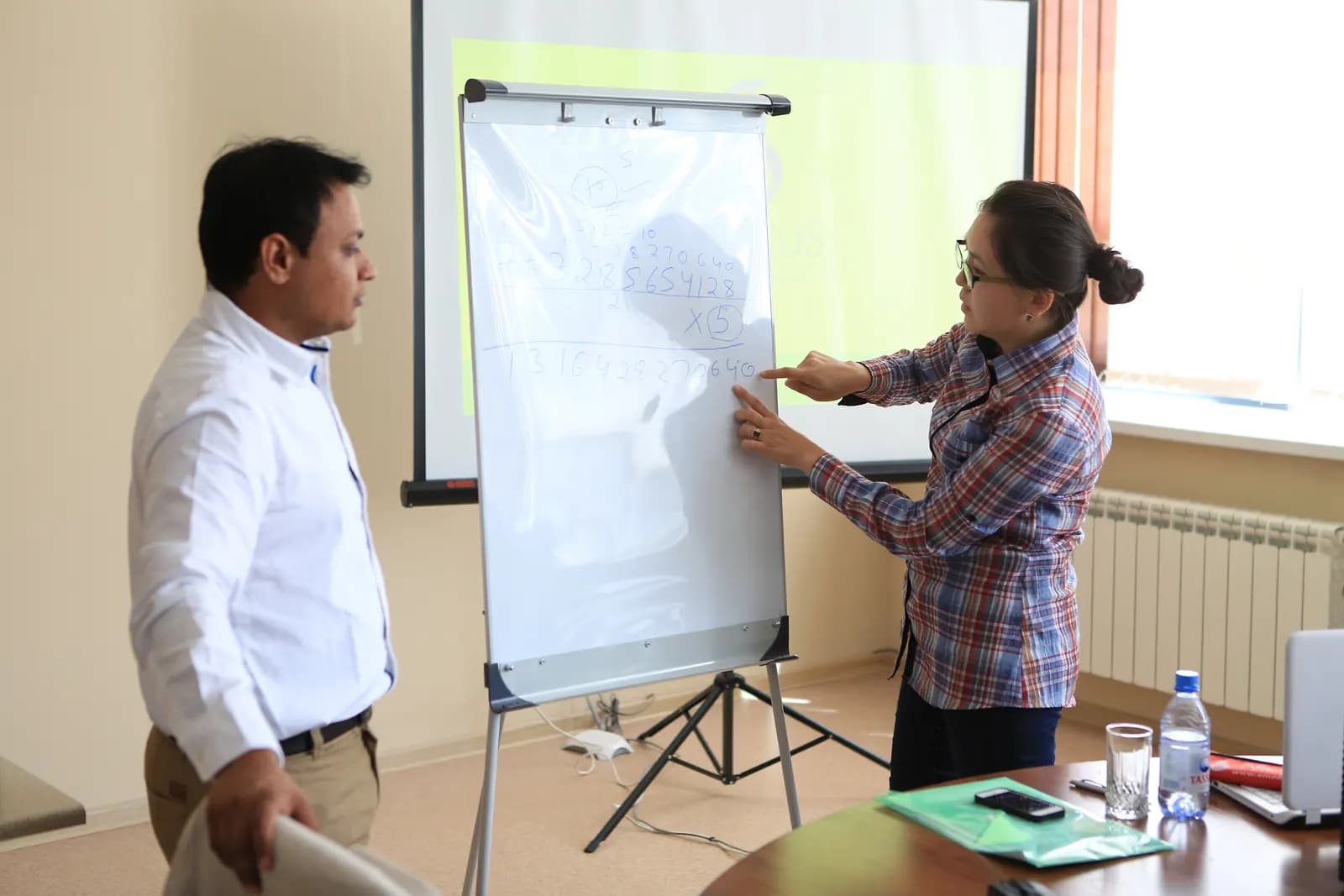 Adults discussing a calculation on a flip chart during a training session